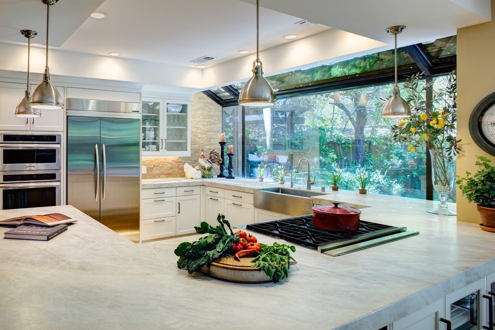 Modern inredning av ett stort kök, med en undermonterad diskho, luckor med infälld panel, vita skåp, marmorbänkskiva, beige stänkskydd, stänkskydd i cementkakel, rostfria vitvaror, mellanmörkt trägolv och en halv köksö