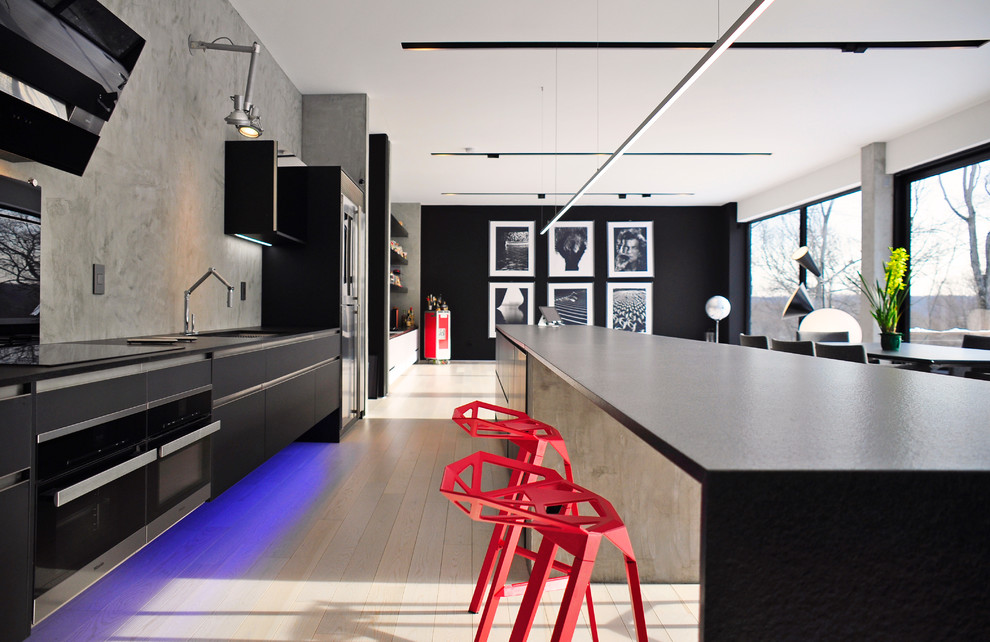 Zweizeilige, Geräumige Moderne Wohnküche mit Glasfronten, schwarzen Schränken, Granit-Arbeitsplatte, Küchenrückwand in Grau, hellem Holzboden, Kücheninsel und beigem Boden in New York