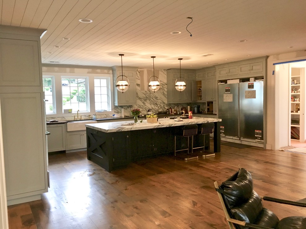 Diseño de cocina clásica renovada con electrodomésticos de acero inoxidable, suelo de madera en tonos medios, una isla y suelo marrón