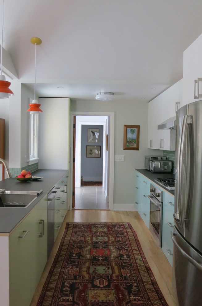 Foto di una cucina parallela moderna di medie dimensioni con lavello a vasca singola, ante lisce, top in vetro e elettrodomestici in acciaio inossidabile