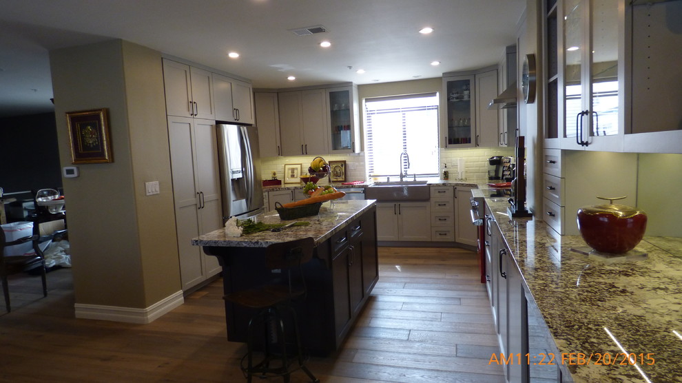 Mid-sized urban single-wall light wood floor eat-in kitchen photo in Los Angeles with a farmhouse sink, shaker cabinets, white cabinets, white backsplash, subway tile backsplash and stainless steel appliances