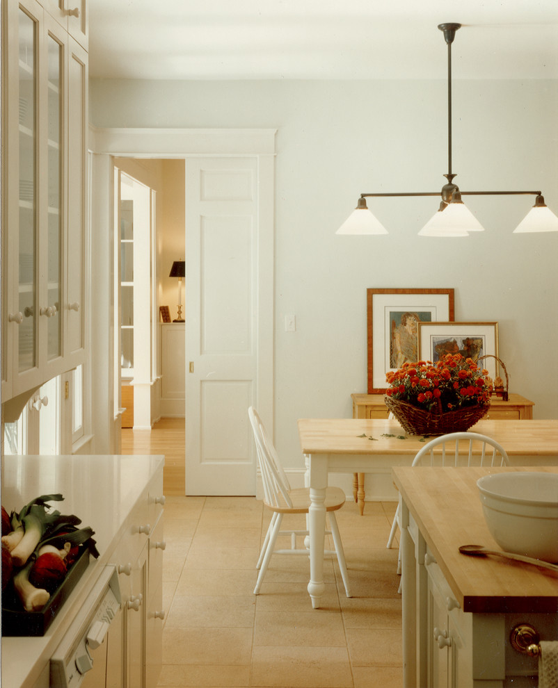ワシントンD.C.にあるトラディショナルスタイルのおしゃれなコの字型キッチン (ガラス扉のキャビネット、白いキャビネット、トラバーチンの床) の写真