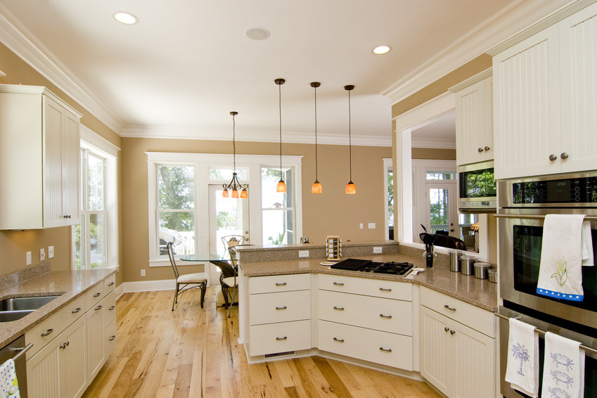 Exempel på ett mellanstort modernt kök, med en dubbel diskho, vita skåp, granitbänkskiva, beige stänkskydd, rostfria vitvaror, ljust trägolv och luckor med infälld panel
