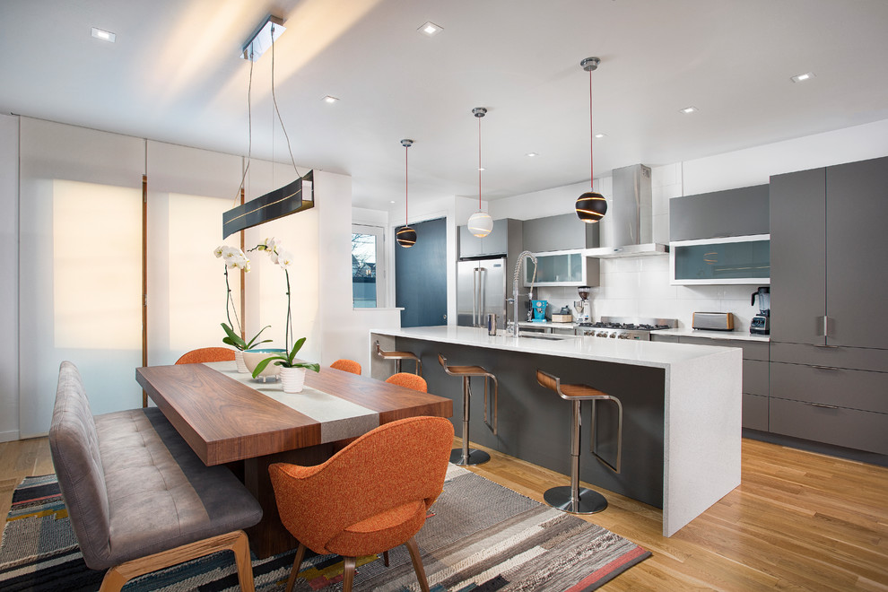 Contemporary kitchen/diner in Denver with a submerged sink, flat-panel cabinets, grey cabinets, white splashback, stainless steel appliances, medium hardwood flooring and an island.