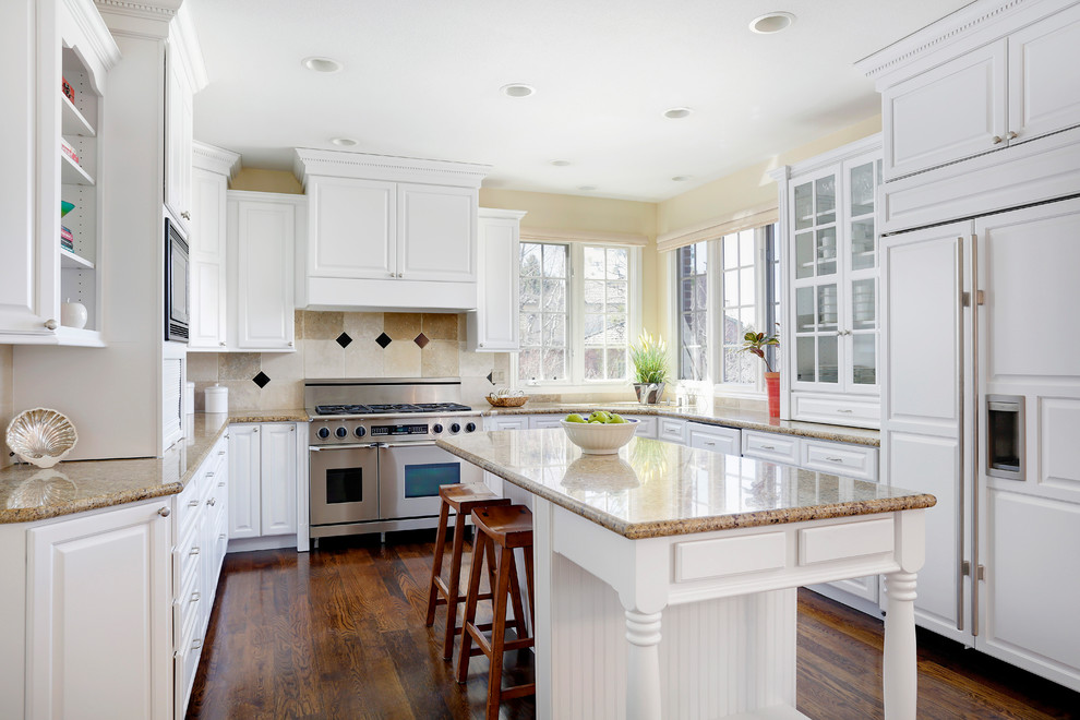 This is an example of a traditional u-shaped kitchen in Denver with raised-panel cabinets, white cabinets, multi-coloured splashback, integrated appliances, dark hardwood flooring and an island.
