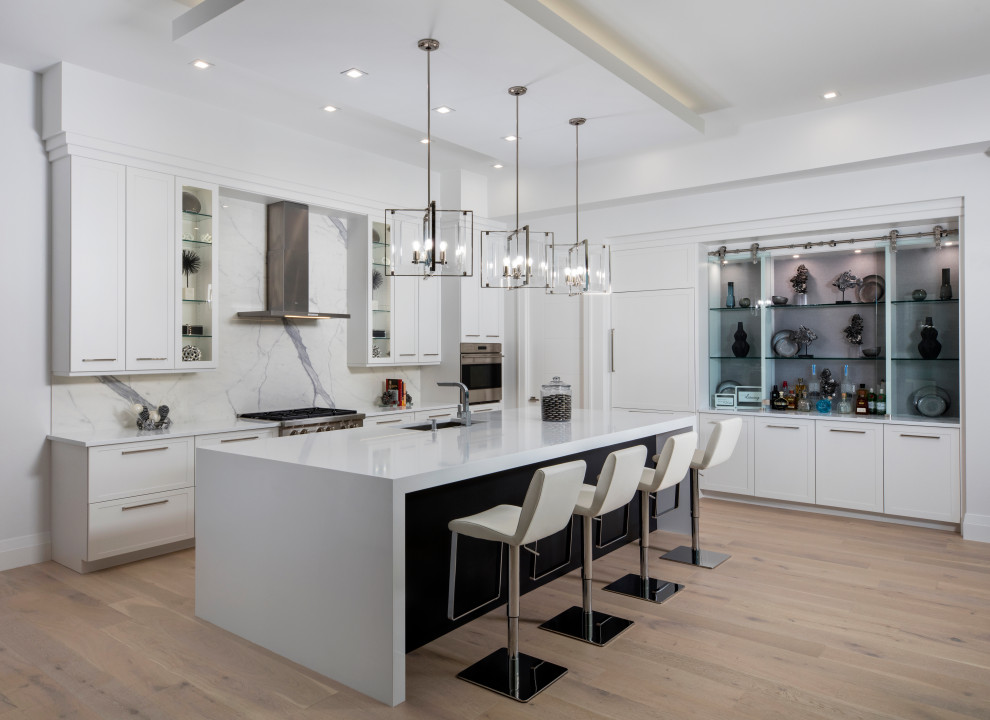 Kitchen - contemporary l-shaped light wood floor and beige floor kitchen idea in Miami with an undermount sink, shaker cabinets, white cabinets, white backsplash, stone slab backsplash, paneled appliances, an island and white countertops