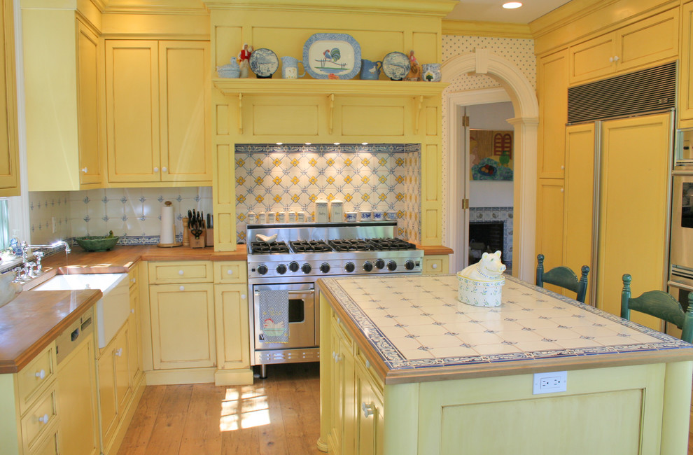 Mittelgroße Landhaus Wohnküche mit Schrankfronten mit vertiefter Füllung, gelben Schränken, Arbeitsplatte aus Fliesen und Kücheninsel in New York