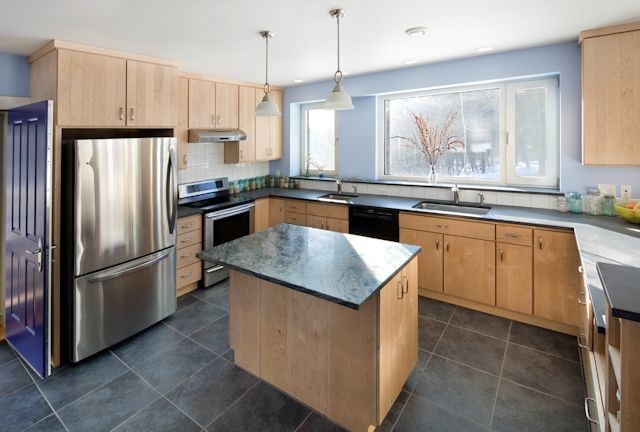 Example of a mid-sized classic l-shaped slate floor eat-in kitchen design in Boston with an undermount sink, flat-panel cabinets, light wood cabinets, granite countertops, white backsplash, ceramic backsplash, stainless steel appliances and a peninsula