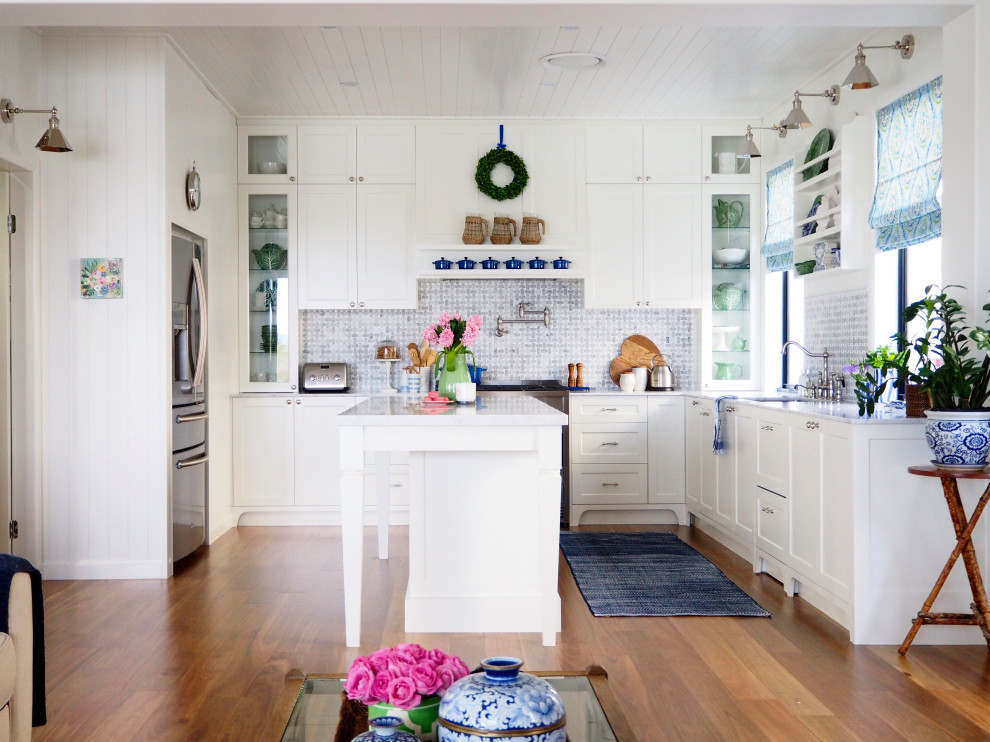 Cette image montre une cuisine marine en L avec un évier encastré, des portes de placard blanches, une crédence bleue et îlot.