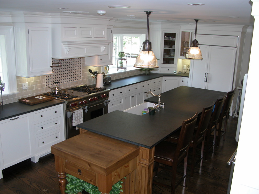 На фото: параллельная кухня в классическом стиле с обеденным столом, с полувстраиваемой мойкой (с передним бортиком), фасадами с утопленной филенкой и белыми фасадами