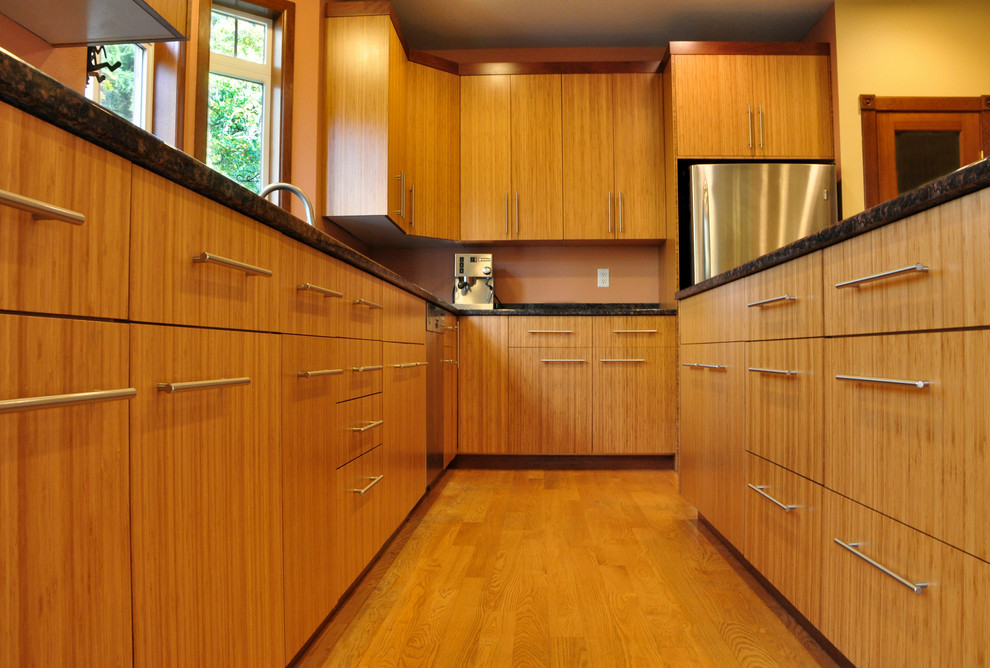 This is an example of a medium sized world-inspired l-shaped kitchen in Seattle with a submerged sink, flat-panel cabinets, light wood cabinets, granite worktops, stainless steel appliances, medium hardwood flooring, an island and brown floors.