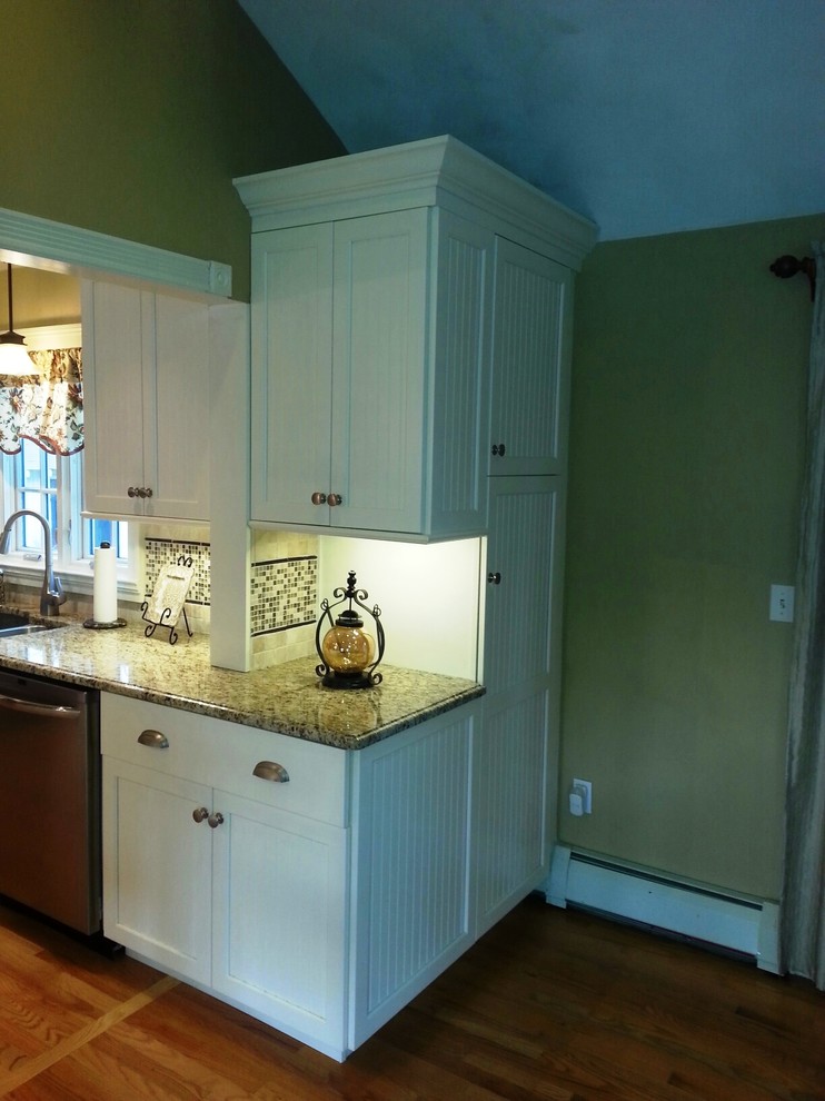 Mid-sized eclectic l-shaped light wood floor open concept kitchen photo in Providence with an undermount sink, recessed-panel cabinets, white cabinets, granite countertops, beige backsplash, ceramic backsplash, stainless steel appliances and an island