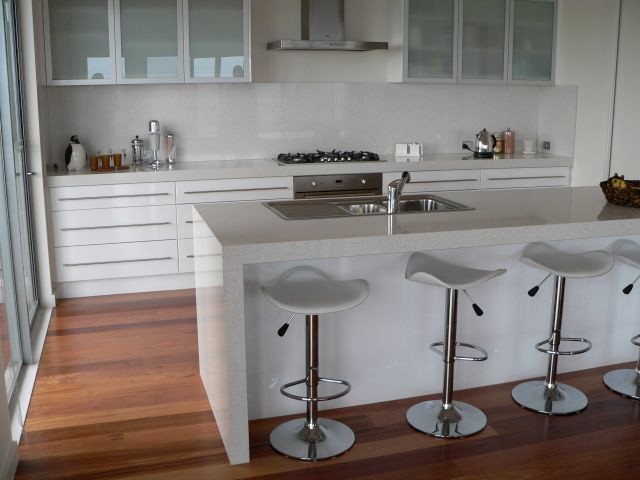 Immagine di una cucina moderna con lavello a doppia vasca, ante lisce, ante bianche, top in quarzo composito, paraspruzzi bianco, paraspruzzi con lastra di vetro, elettrodomestici in acciaio inossidabile e parquet scuro