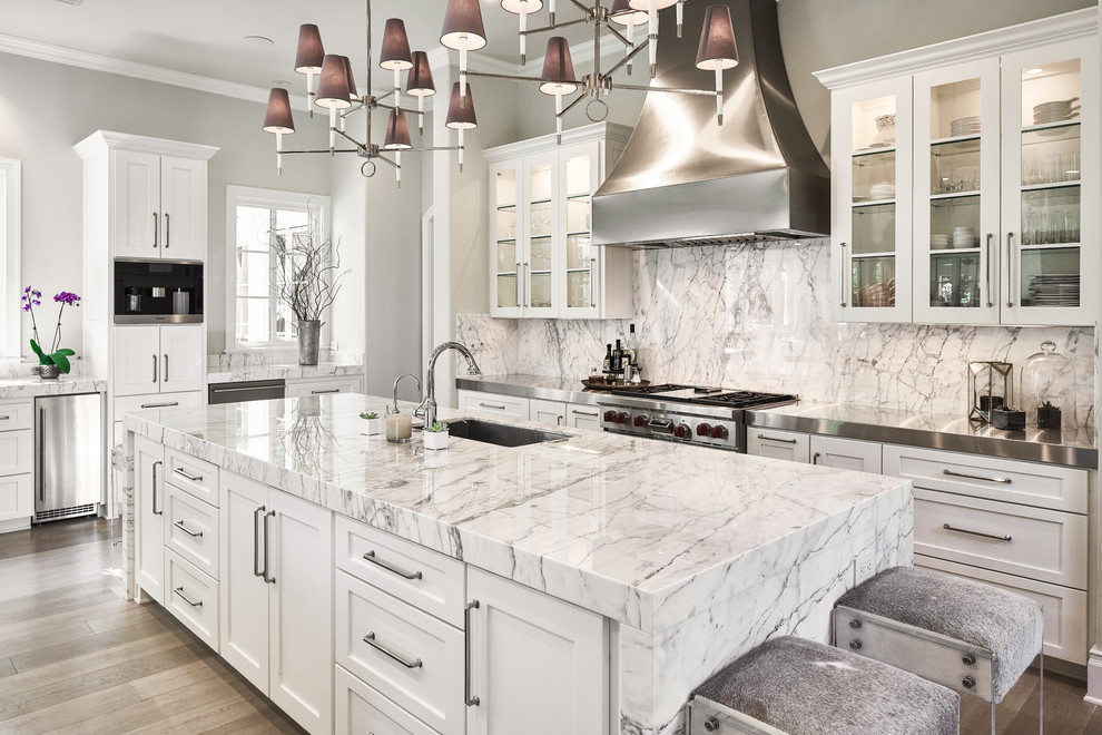 Esempio di una cucina minimal con ante di vetro, ante bianche, top in marmo, paraspruzzi grigio, elettrodomestici in acciaio inossidabile e 2 o più isole