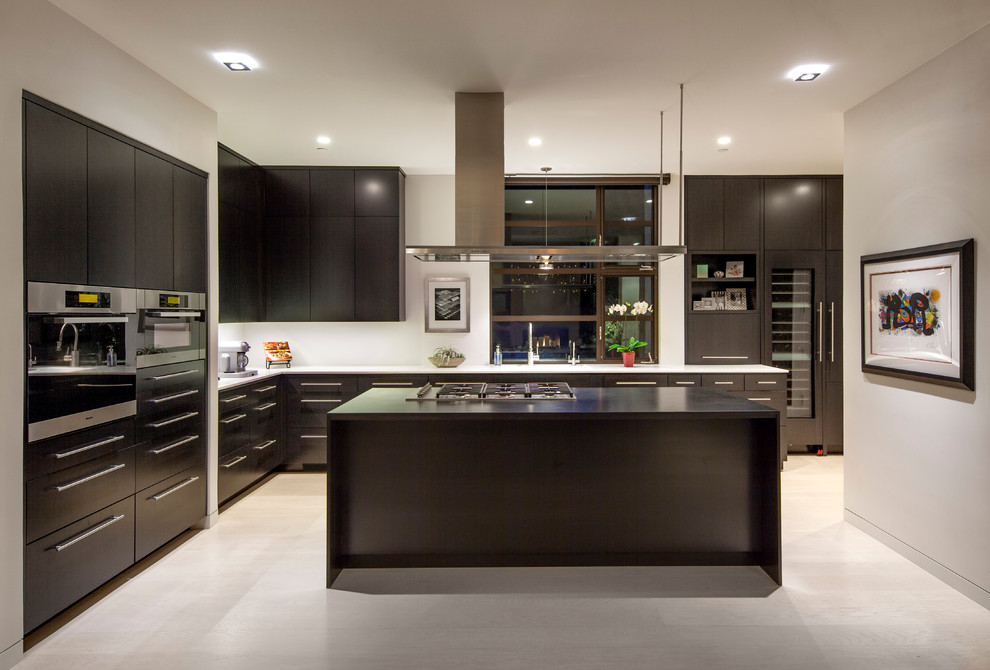Esempio di una cucina design con ante lisce, ante nere, top in marmo, elettrodomestici in acciaio inossidabile e parquet chiaro