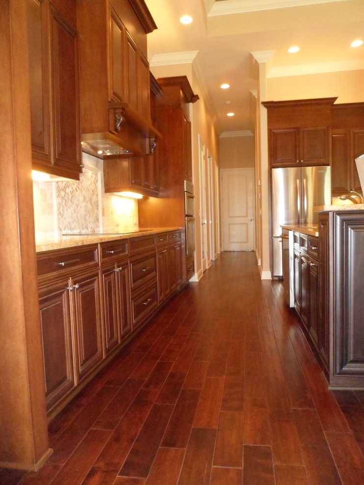 Example of a mid-sized classic l-shaped dark wood floor and brown floor eat-in kitchen design in Tampa with a double-bowl sink, raised-panel cabinets, dark wood cabinets, granite countertops, beige backsplash, ceramic backsplash, stainless steel appliances and an island