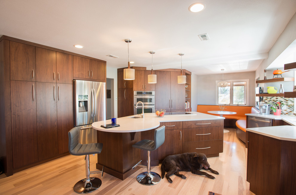 Moderne Küche mit Unterbauwaschbecken, flächenbündigen Schrankfronten, dunklen Holzschränken, Küchengeräten aus Edelstahl, hellem Holzboden und Kücheninsel in Denver