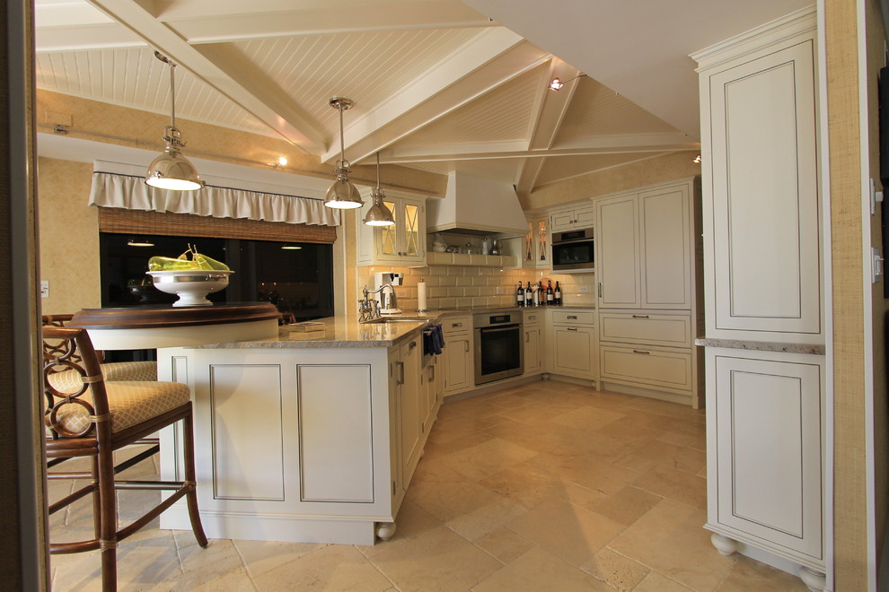 Mid-sized elegant l-shaped terra-cotta tile and beige floor eat-in kitchen photo in Miami with a farmhouse sink, recessed-panel cabinets, beige cabinets, marble countertops, beige backsplash, subway tile backsplash, stainless steel appliances and a peninsula