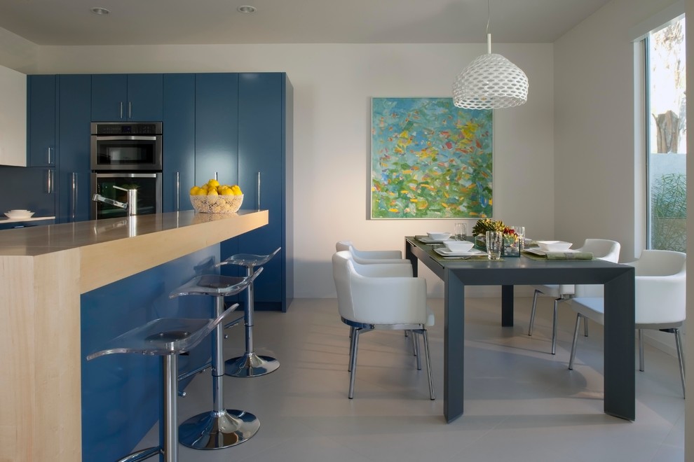 Medium sized contemporary l-shaped kitchen/diner in Los Angeles with a submerged sink, flat-panel cabinets, blue cabinets, engineered stone countertops, white splashback, stone slab splashback, stainless steel appliances, porcelain flooring, an island and grey floors.