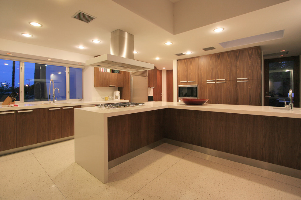 Large contemporary u-shaped open plan kitchen in Los Angeles with a double-bowl sink, flat-panel cabinets, dark wood cabinets, engineered stone countertops, white splashback, stone slab splashback, stainless steel appliances, ceramic flooring, an island and beige floors.