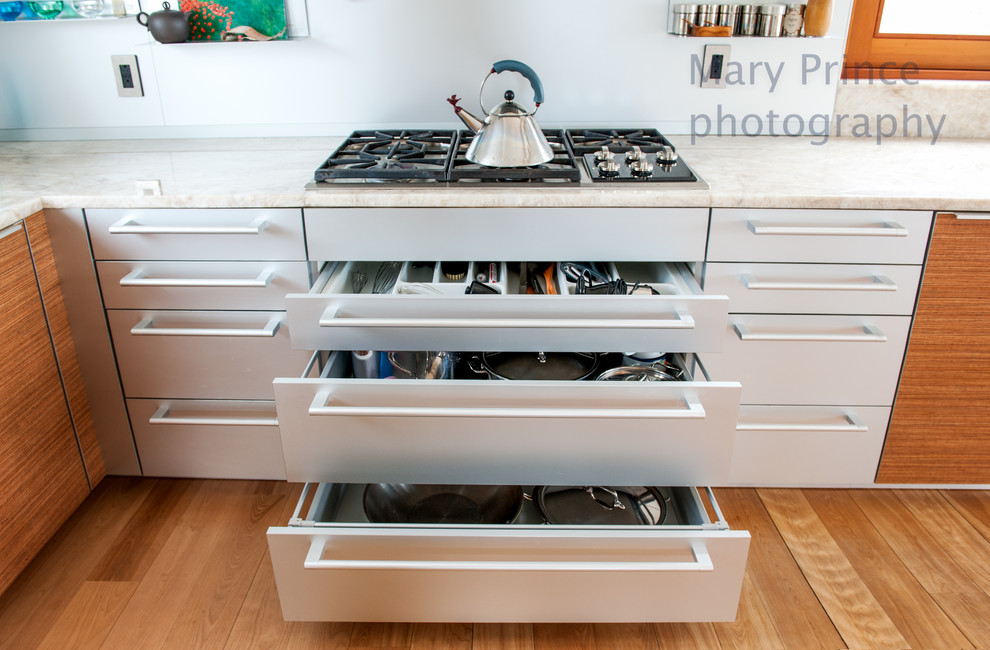 Inspiration for a contemporary kitchen in Boston with flat-panel cabinets, stainless steel cabinets, light hardwood flooring and an island.