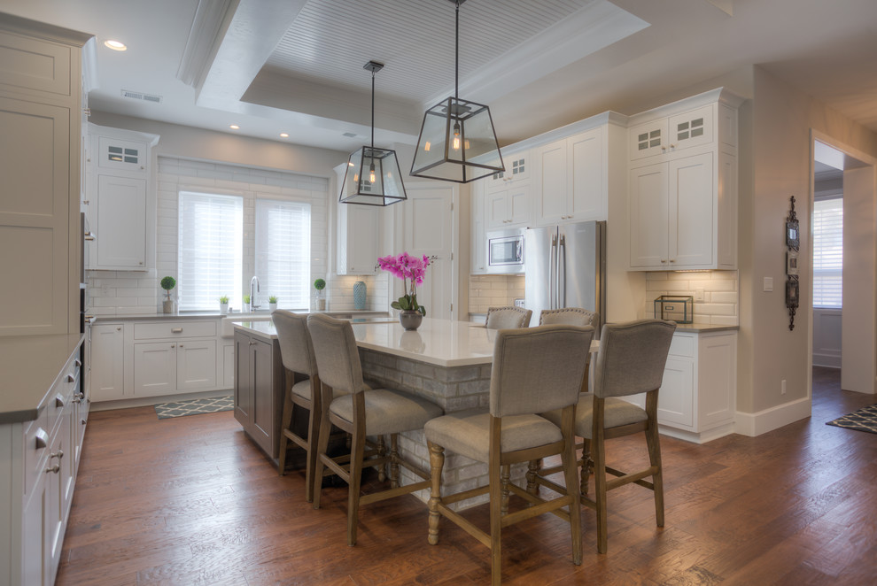 Mid-sized arts and crafts u-shaped limestone floor eat-in kitchen photo in Albuquerque with a farmhouse sink, shaker cabinets, white cabinets, quartzite countertops, white backsplash, subway tile backsplash, stainless steel appliances and an island