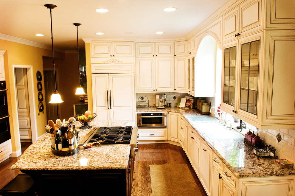 Klassisk inredning av ett mellanstort kök, med en undermonterad diskho, skåp i shakerstil, vita skåp, granitbänkskiva, beige stänkskydd, stänkskydd i tunnelbanekakel, rostfria vitvaror, mellanmörkt trägolv, en köksö och brunt golv