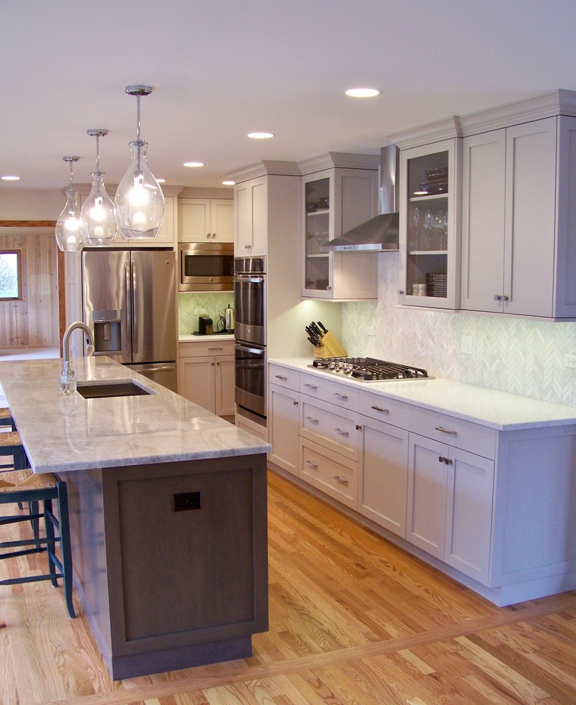 Inspiration for a mid-sized transitional l-shaped light wood floor and beige floor open concept kitchen remodel in Chicago with an undermount sink, shaker cabinets, gray cabinets, marble countertops, white backsplash, porcelain backsplash, stainless steel appliances and an island