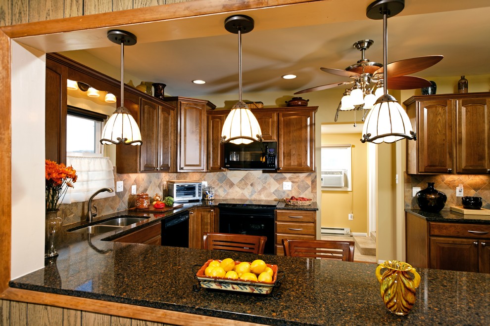 Exempel på ett klassiskt kök, med en dubbel diskho, skåp i mellenmörkt trä, granitbänkskiva, beige stänkskydd, stänkskydd i mosaik och svarta vitvaror