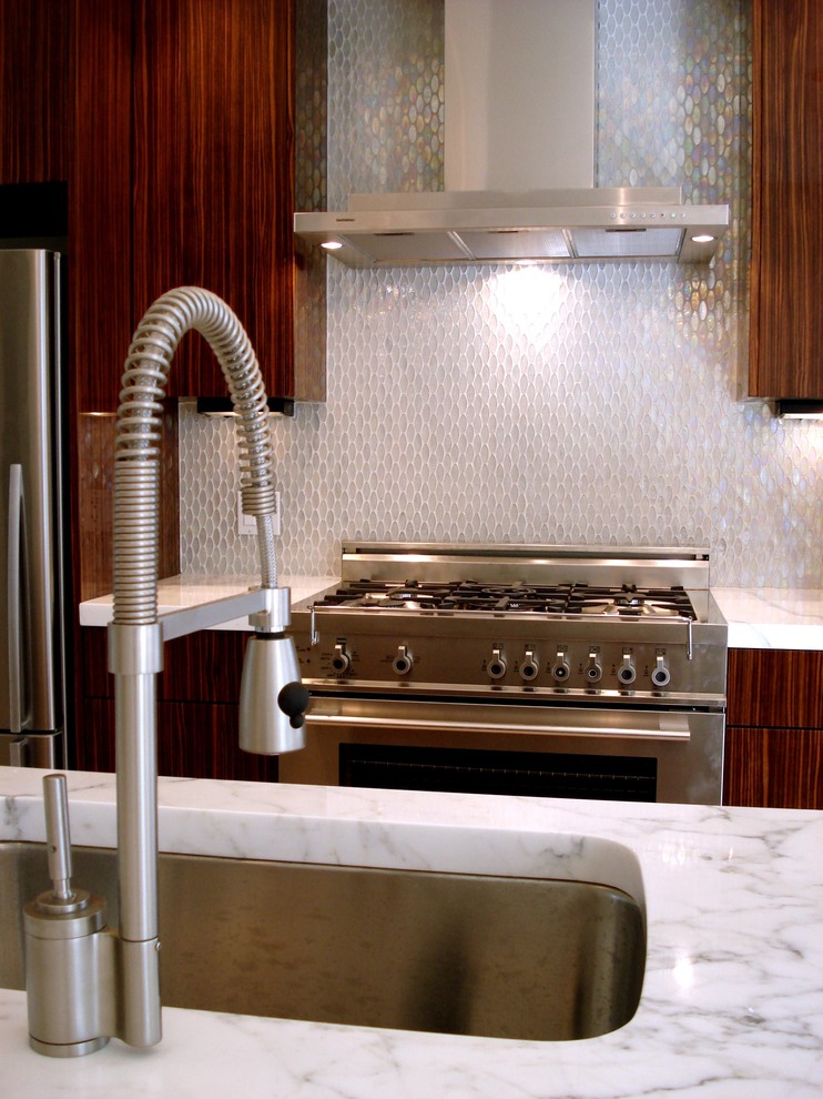 Imagen de cocina contemporánea con electrodomésticos de acero inoxidable, fregadero bajoencimera, armarios con paneles lisos, puertas de armario de madera en tonos medios, salpicadero blanco y salpicadero con mosaicos de azulejos