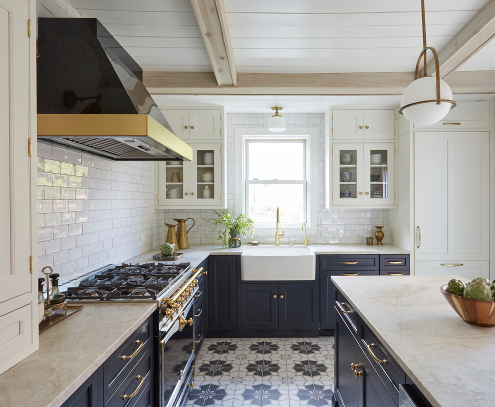 Foto på ett lantligt l-kök, med en rustik diskho, skåp i shakerstil, blå skåp, vitt stänkskydd, stänkskydd i tunnelbanekakel, integrerade vitvaror, en köksö och flerfärgat golv
