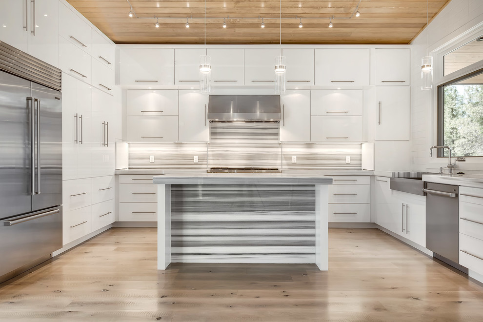 Moderne Küche in grau-weiß in U-Form mit flächenbündigen Schrankfronten, weißen Schränken, bunter Rückwand, Küchengeräten aus Edelstahl, hellem Holzboden und Kücheninsel in Denver