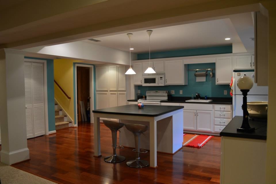 Offene, Mittelgroße Moderne Küche in L-Form mit flächenbündigen Schrankfronten, weißen Schränken, Glas-Arbeitsplatte, weißen Elektrogeräten, braunem Holzboden und Kücheninsel in Atlanta