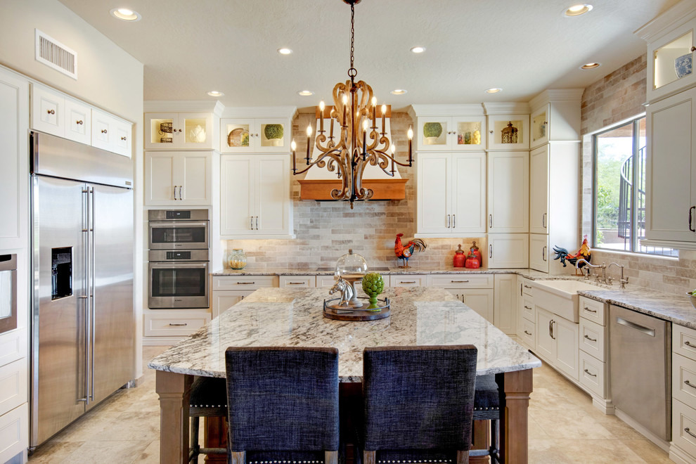 Inspiration for a large transitional u-shaped travertine floor and beige floor open concept kitchen remodel in Phoenix with recessed-panel cabinets, white cabinets, granite countertops, an island, multicolored countertops, a farmhouse sink, gray backsplash, porcelain backsplash and stainless steel appliances