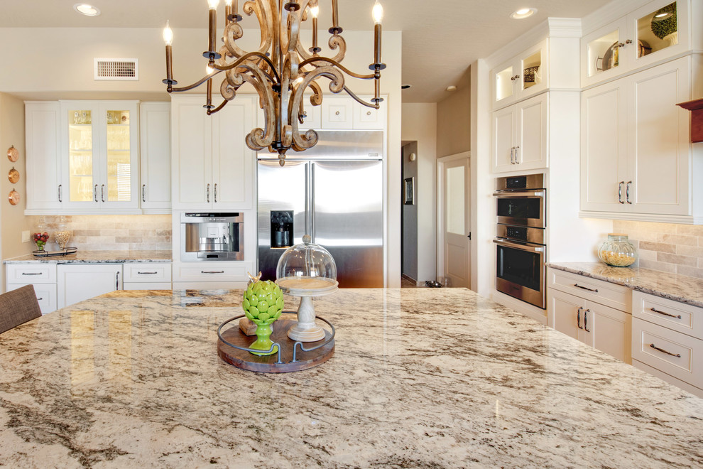 Inspiration for a large transitional u-shaped travertine floor and beige floor open concept kitchen remodel in Phoenix with recessed-panel cabinets, white cabinets, granite countertops, an island, multicolored countertops, a farmhouse sink, gray backsplash, porcelain backsplash and stainless steel appliances