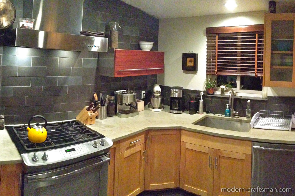 Moderne Wohnküche in L-Form mit flächenbündigen Schrankfronten, hellbraunen Holzschränken, Betonarbeitsplatte, Küchenrückwand in Grau, Rückwand aus Steinfliesen, Küchengeräten aus Edelstahl und Schieferboden in Salt Lake City