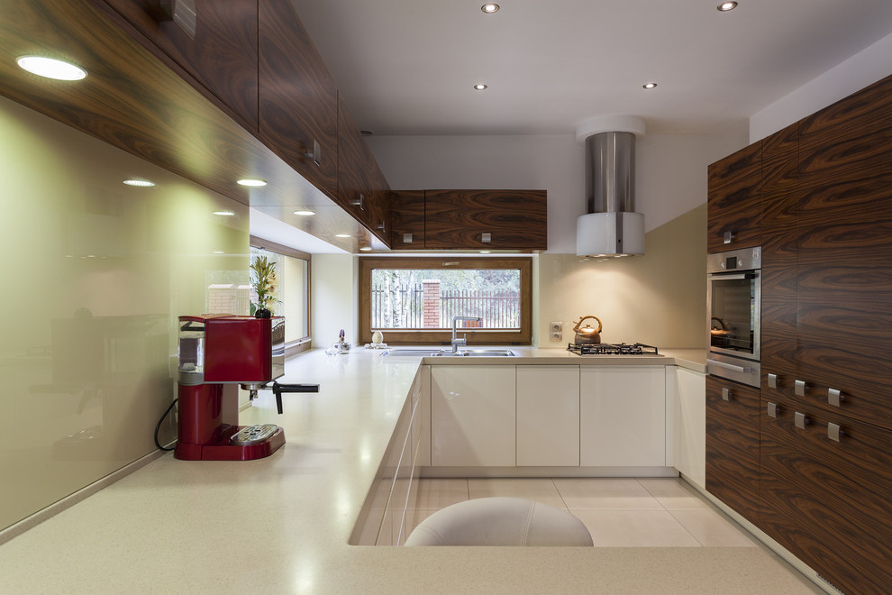 Immagine di una cucina moderna di medie dimensioni con ante lisce, ante in legno bruno, paraspruzzi verde e elettrodomestici in acciaio inossidabile