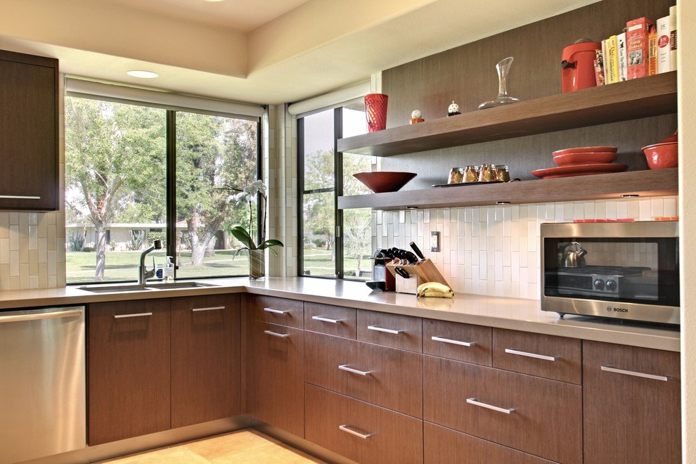 Example of a mid-sized 1960s l-shaped eat-in kitchen design in Los Angeles with a double-bowl sink, flat-panel cabinets, medium tone wood cabinets, white backsplash and stainless steel appliances