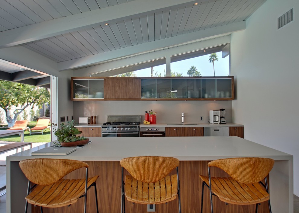 Mid-sized trendy single-wall concrete floor eat-in kitchen photo in Los Angeles with a double-bowl sink, flat-panel cabinets, medium tone wood cabinets, white backsplash, stainless steel appliances and an island