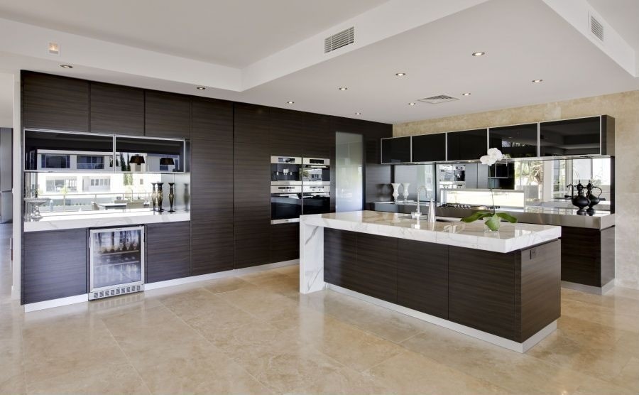 Inspiration for a large traditional l-shaped open plan kitchen in Los Angeles with a submerged sink, flat-panel cabinets, beige cabinets, granite worktops, metallic splashback, mirror splashback, stainless steel appliances, limestone flooring, an island and beige floors.