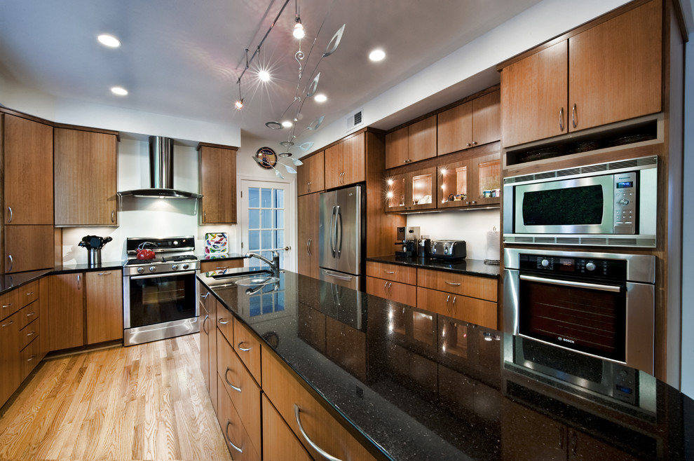 Foto de cocina comedor contemporánea de tamaño medio con armarios con paneles lisos, puertas de armario de madera oscura, electrodomésticos de acero inoxidable, suelo de madera en tonos medios y una isla