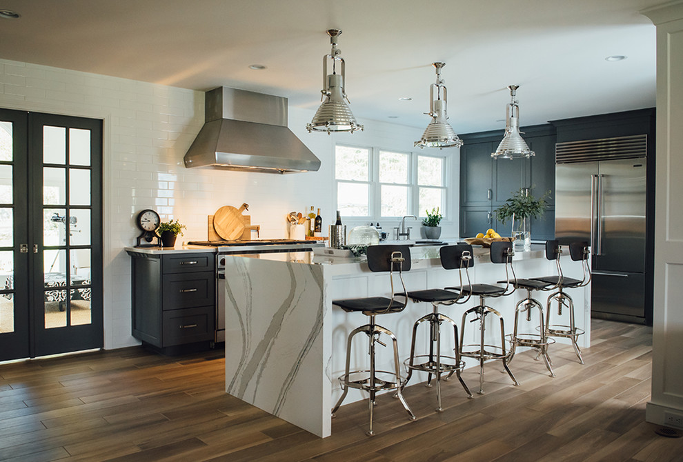 Inspiration for a transitional l-shaped medium tone wood floor and brown floor eat-in kitchen remodel in Louisville with recessed-panel cabinets, black cabinets, white backsplash, stainless steel appliances, an island and white countertops