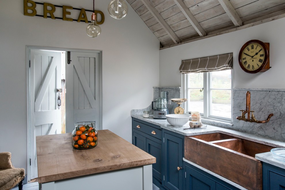 На фото: кухня в стиле кантри с с полувстраиваемой мойкой (с передним бортиком), фасадами в стиле шейкер, синими фасадами, островом и шторами на окнах