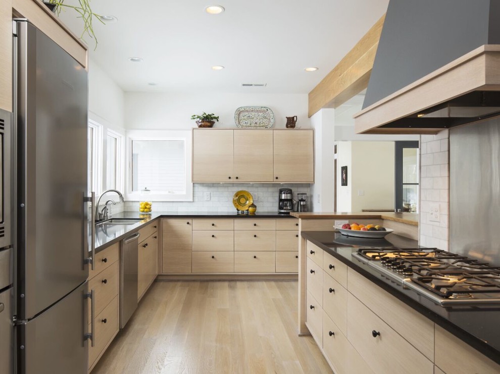 Example of a large trendy l-shaped light wood floor and beige floor enclosed kitchen design in Los Angeles with a double-bowl sink, flat-panel cabinets, light wood cabinets, quartz countertops, white backsplash, marble backsplash and stainless steel appliances