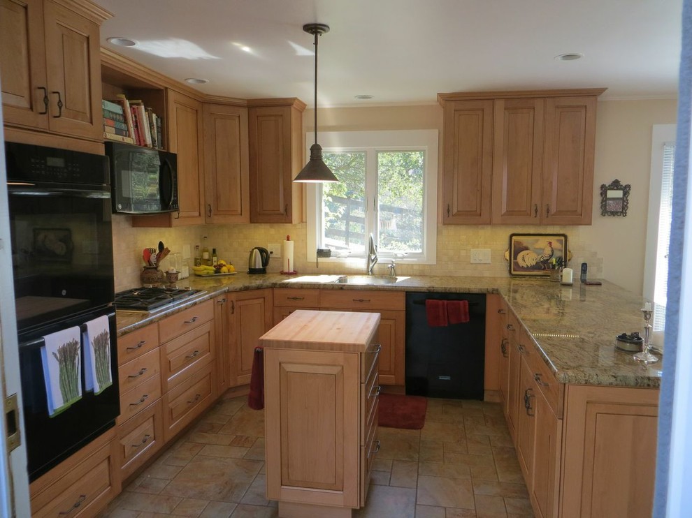 Foto på ett avskilt, mellanstort lantligt u-kök, med luckor med upphöjd panel, skåp i ljust trä, granitbänkskiva, beige stänkskydd, stänkskydd i stenkakel, svarta vitvaror och en köksö
