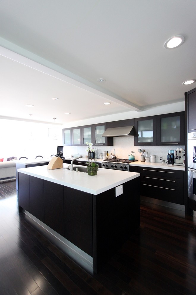 Example of a large minimalist l-shaped dark wood floor eat-in kitchen design in Orange County with an undermount sink, flat-panel cabinets, black cabinets, quartz countertops, white backsplash, ceramic backsplash, stainless steel appliances and an island