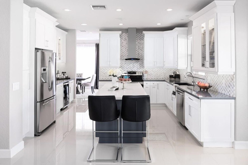 Example of a mid-sized trendy l-shaped porcelain tile and white floor kitchen pantry design in Other with a drop-in sink, flat-panel cabinets, white cabinets, quartz countertops, multicolored backsplash, ceramic backsplash, stainless steel appliances, an island and gray countertops