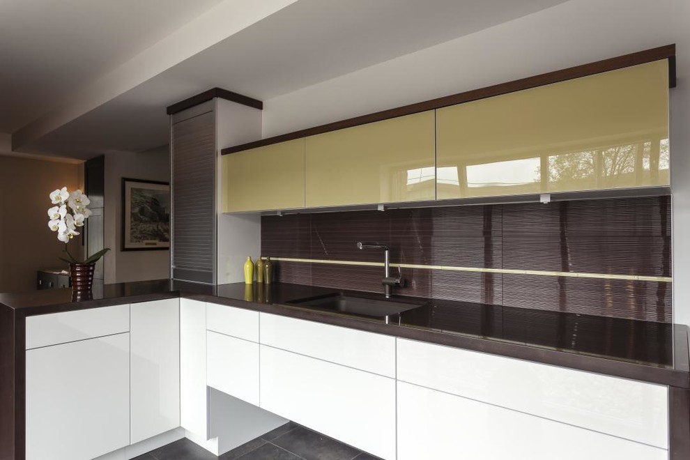 Large contemporary l-shaped kitchen/diner in DC Metro with a single-bowl sink, flat-panel cabinets, white cabinets, granite worktops, white splashback, ceramic splashback, stainless steel appliances and ceramic flooring.