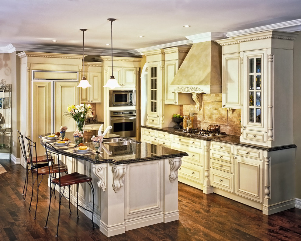 Inredning av ett klassiskt stort kök, med en undermonterad diskho, luckor med infälld panel, vita skåp, granitbänkskiva, beige stänkskydd, stänkskydd i stenkakel, integrerade vitvaror, mörkt trägolv, en köksö och brunt golv