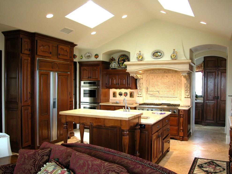 Imagen de cocina clásica, abierta, con electrodomésticos con paneles y puertas de armario de madera en tonos medios